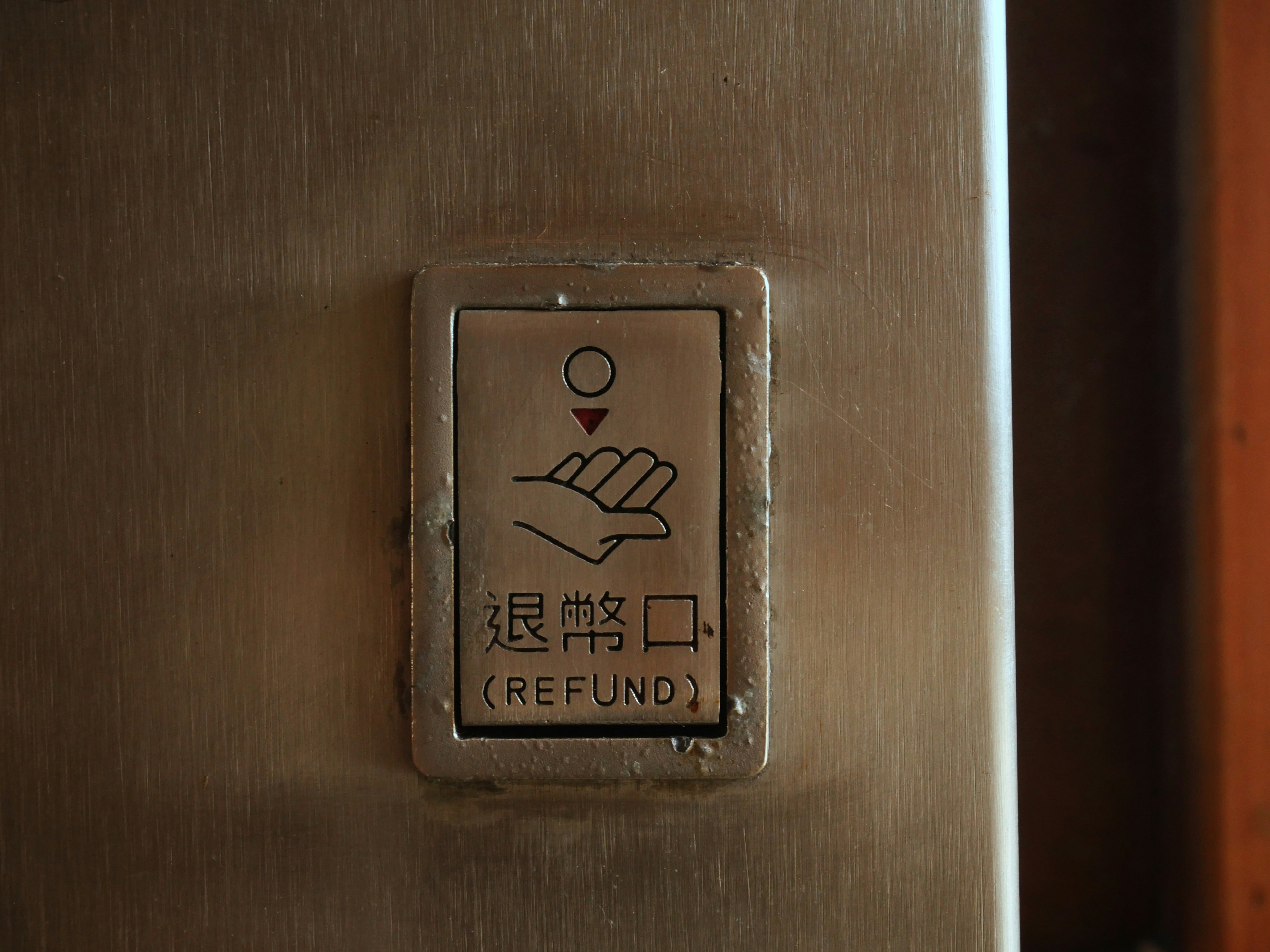 A metal panel with a sign depicting a hand and a coin above it. Below the illustration, there are Chinese characters and the word 'REFUND' in English.